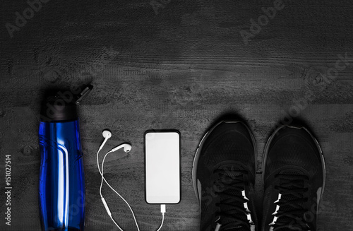 Sports equipment - sneakers, skipping rope, dumbbells, smartphone and headphones. Sport background on wooden floor, top view photo