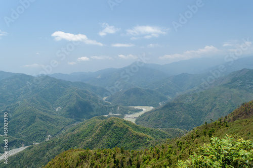A hilltop view of mountains and blue sky with clouds  on a misty day. © ABIR