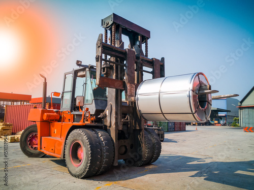 The forklift is handling big coil to warehouse after unstuffing from container. photo
