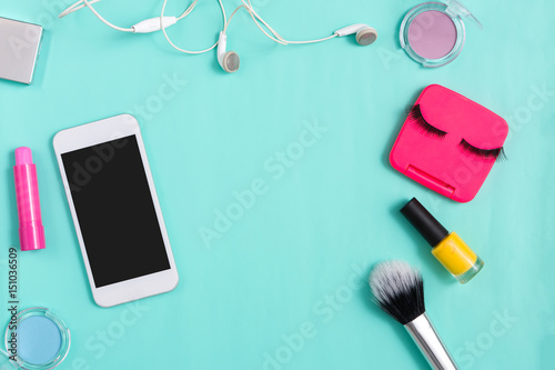 Beauty products, everyday make-up and mobile on blue