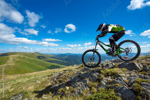 Fototapeta Naklejka Na Ścianę i Meble -  A man is riding bicycle, on the background of mountains and blue sky. Beautiful summer day.