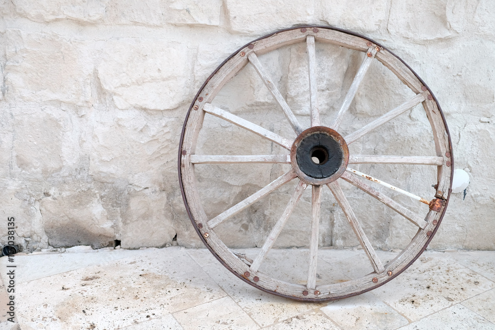 Old wheel of cart leaned on the brick wall