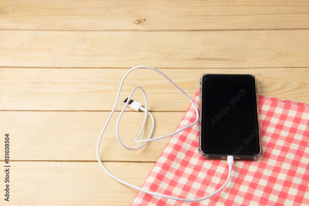 Black Cell phone on red napkin on wooden table, high angle view Black Cell phone on red napkin on wooden table, high angle view