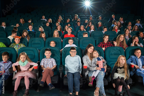 People watching a movie in a dark cinema hall parents kids children family weekend holidays entertainment fun activity leisure hobby premiere comedy cartoons childhood concept.