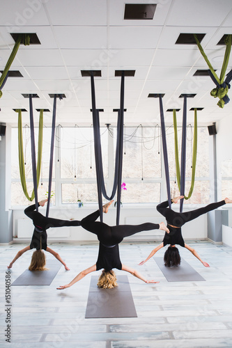 Young women doing aerial yoga exercise 