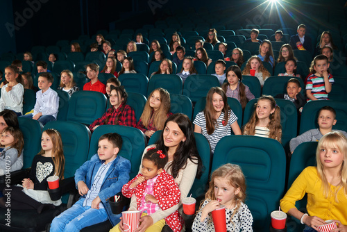 Cinema hall full of children and their parents enjoying movie premiere together entertainment activity hobby lifestyle people emotions excitement amusement expressive concept.