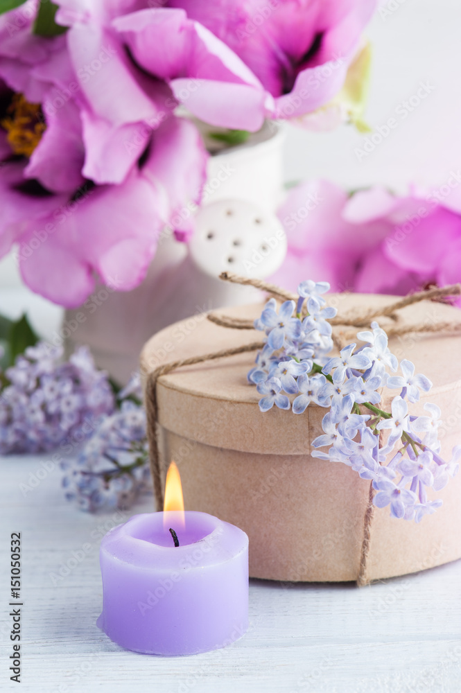 Lit candle, peonies and lilac flowers