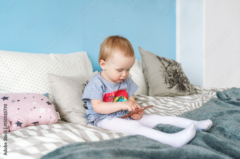 Naklejka premium Portrait of a cute baby girl with a mobile phone