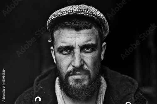 Black and white portrait of homeless poor man smoking in camera.	