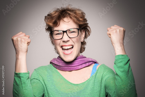 Happy elegant laughing beautiful woman celebrating her success and looking at camera isolated on the grey background