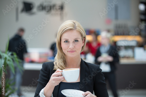 Young beautiful business woman drinking a cup of coffee or tea