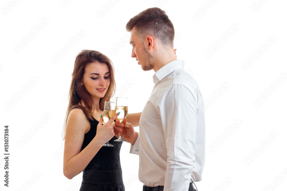 beautiful young girl stands with a guy in a white shirt and drinking champagne from glasses beautiful young girl stands with a guy in a white shirt and drinking champagne from glasses