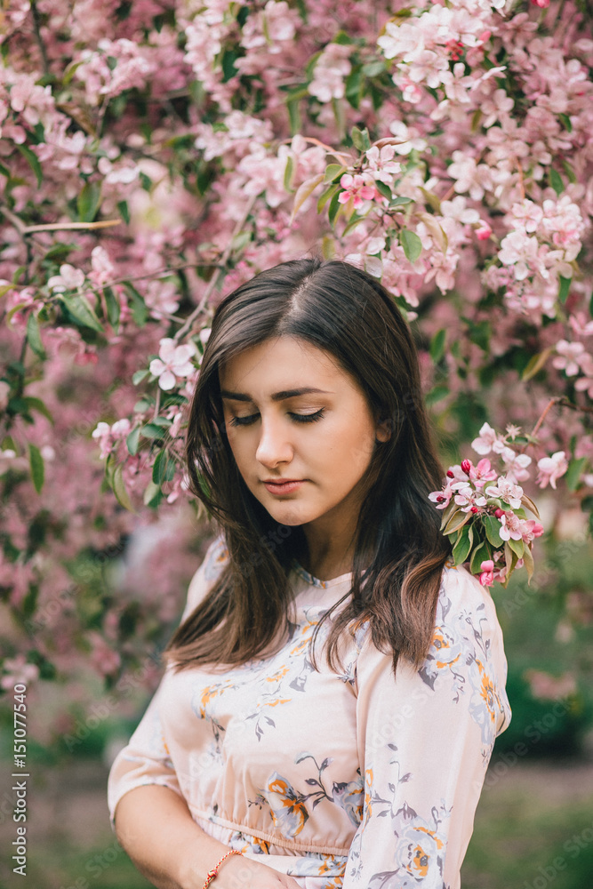 Portrait of a beautiful woman standing near a pink flowering apple tree Portrait of a beautiful woman standing near a pink flowering apple tree