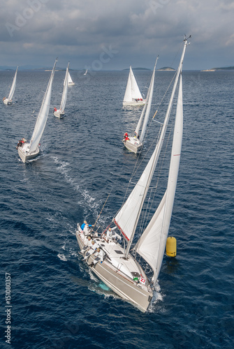 Obraz na plátně Coming fleet of sailing boats during offshore race passing yellow buoy, bird vie