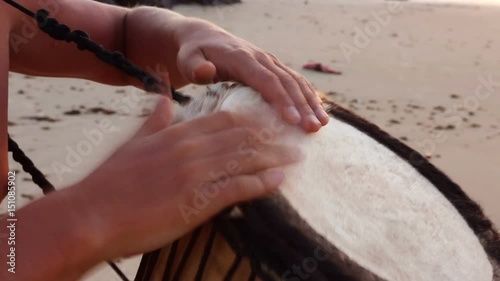 Drum Jembe playing. Drummer. Male hands with Jembe close-up. Man Playing Drum. Action, percussion instrument. Musician playing Live ethno Music at sunset On the beach. Rhythm of summer