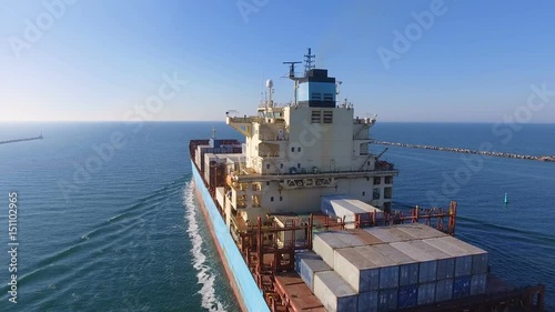 Aerial view of container ship passes through the channel goes into the open ocean after loading in the port of China at full speed. 4K.