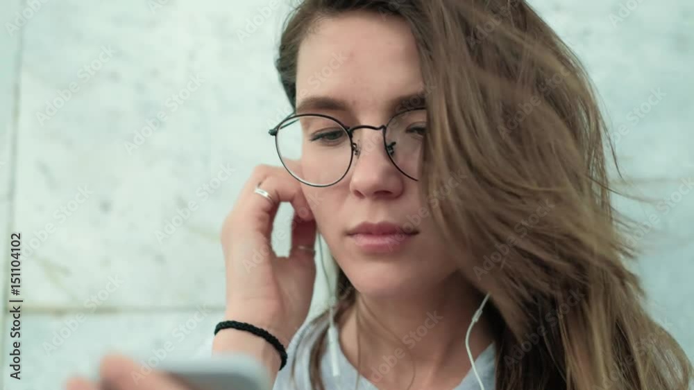 Beautiful brunette girl in glasses on a background of gray marble wall included pleasant music and enjoys Beautiful brunette girl in glasses on a background of gray marble wall included pleasant music and enjoys
