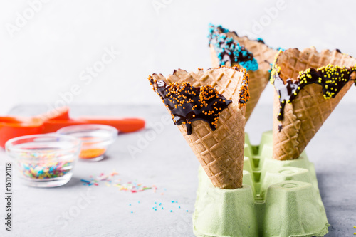 Preparing chocolate dipped ice cream cones with candy  sprinkles