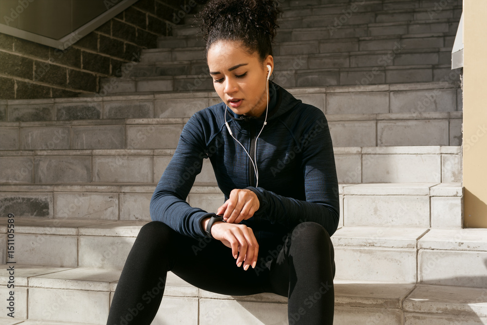 Young female runner checking her pulse with an activity tracker after training Young female runner checking her pulse with an activity tracker after training