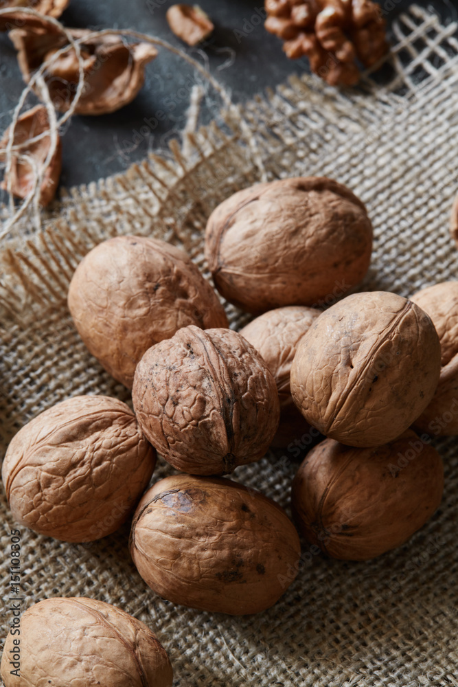 Walnuts and kernels with burlap fabric on a grey concrete backdrop Walnuts and kernels with burlap fabric on a grey concrete backdrop