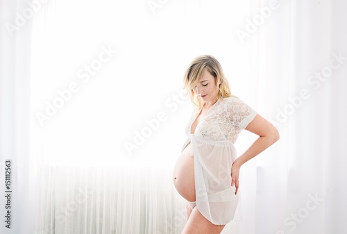 Happy young attractive pregnant woman in white shirt