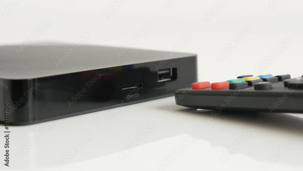 Tilting on black set-top-box with IR controller 4K 2160p 30fps UltraHD video - STB TV device and infrared remote on white background slow tilt 3840X2160 UHD footage Tilting on black set-top-box with IR controller 4K 2160p 30fps UltraHD video - STB TV device and infrared remote on white background slow tilt 3840X2160 UHD footage