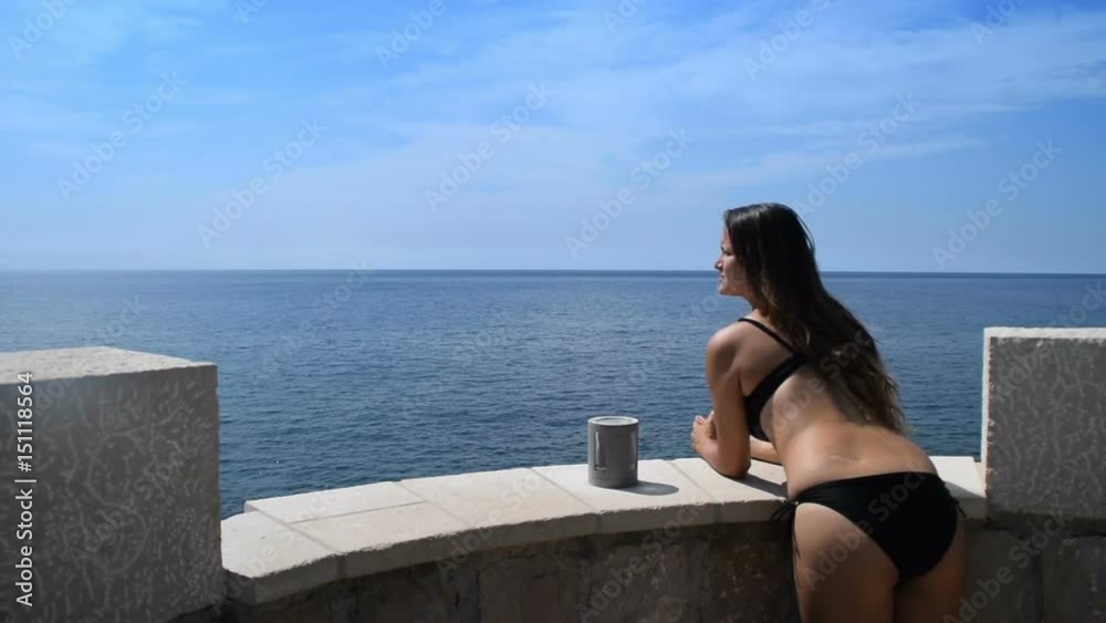young woman in a bikini coming out onto the balcony to enjoy the beauty of the open sea young woman in a bikini coming out onto the balcony to enjoy the beauty of the open sea