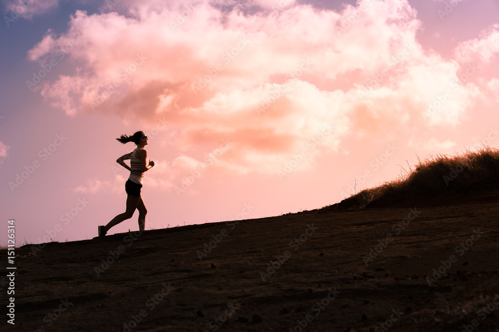 Silhouette of female running up a hill. 
