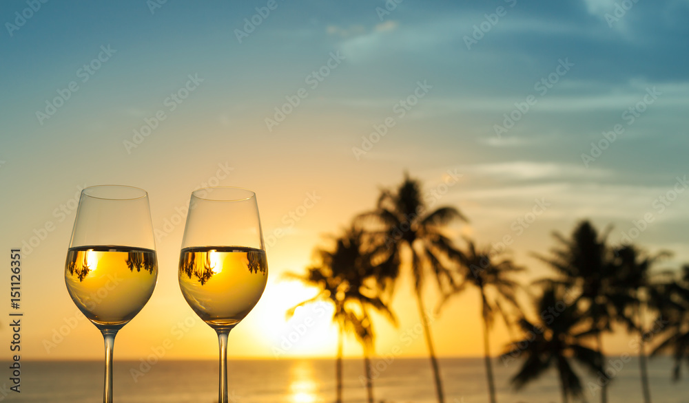 Romantic beach holiday retreat concept. Pair of wine glasses against a beautiful beach setting. 