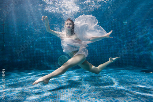 Woman dances underwater sports dance  her dress fluttering under the water.