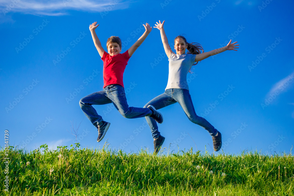 Two kids jumping together on green spring hills Two kids jumping together on green spring hills
