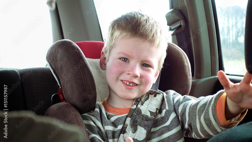 Little cute boy in a car seat smiles and laughs. Pure fun happy and playful emotions over child face. Little cute boy in a car seat smiles and laughs. Pure fun happy and playful emotions over child face.