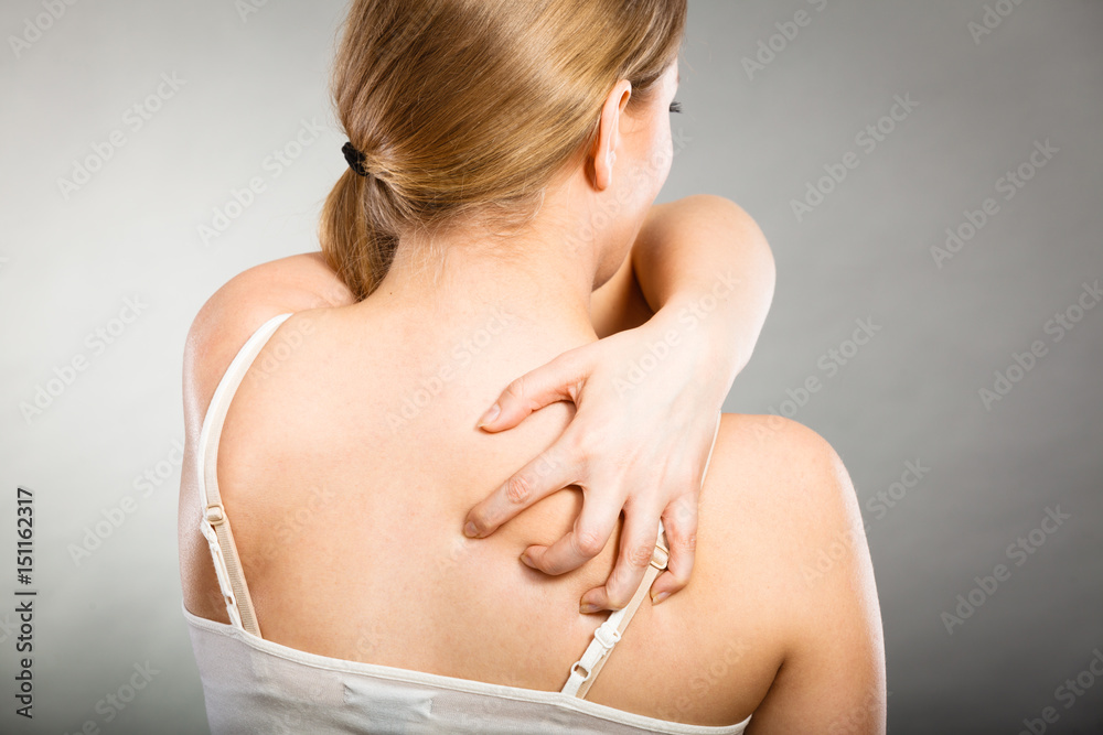 woman scratching her itchy back with allergy rash woman scratching her itchy back with allergy rash