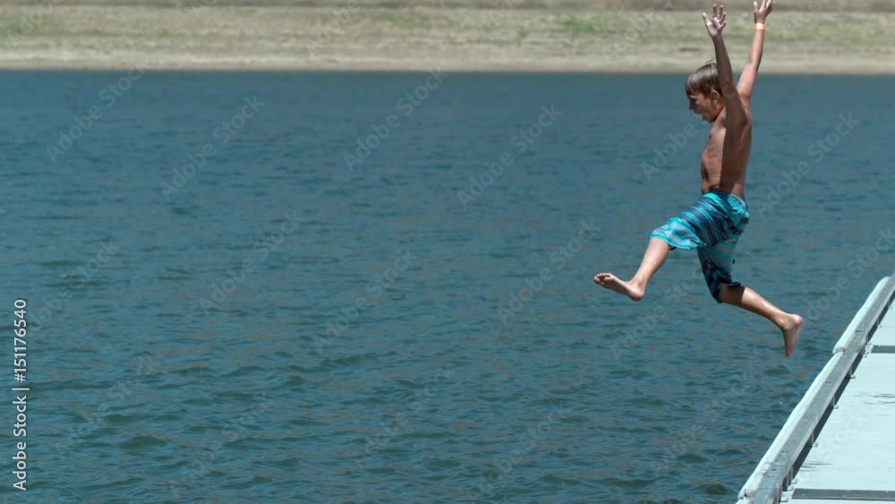 Boy jumping off dock into lake in super slow motion