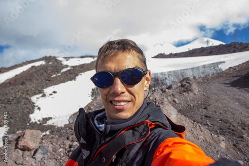 A man makes selfie against the background of a mountain in the region of Elbrus