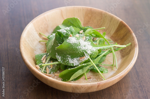 Fresh salad with mixed greens (arugula, mesclun, mache) on light wooden background close up. Healthy food.