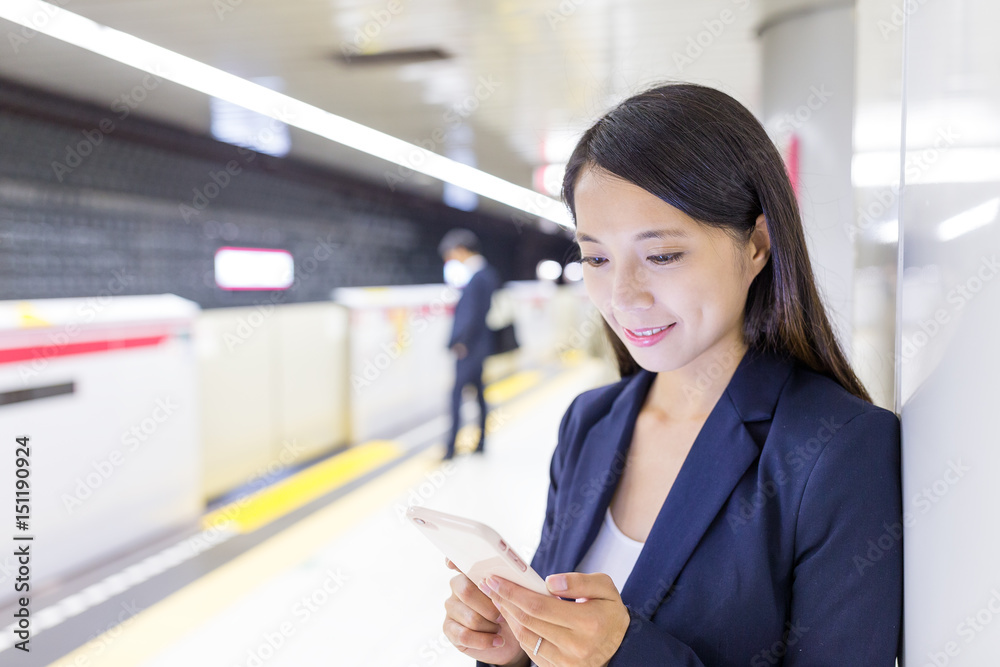 Businesswoman working on cellphone in train platform