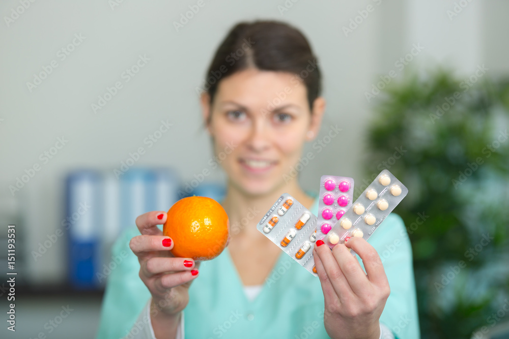 nurse holding orange in one hand medication in the other nurse holding orange in one hand medication in the other
