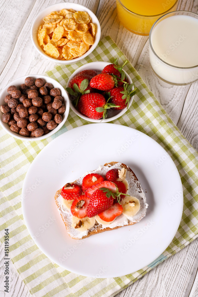 breakfast: Fresh toast with strawberry, banana and nuts, cornflakes, orange juice, milk