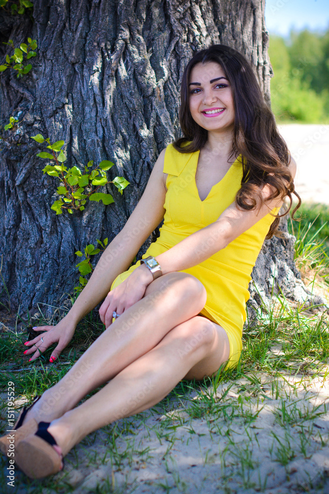 Charming Latin girl in a yellow short dress with a good mood resting on vacation and enjoying life laughing and smiling Charming Latin girl in a yellow short dress with a good mood resting on vacation and enjoying life laughing and smiling