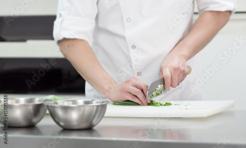 chef chopped fresh green onion on cutting board in kitchen