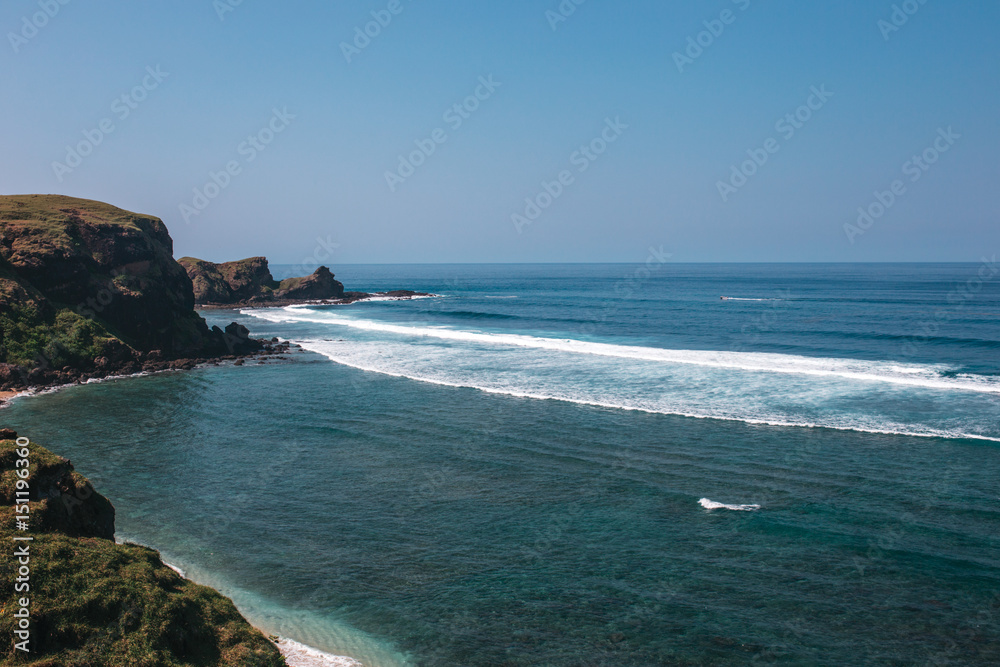 Rocky coast of the ocean with green hills and azure water, Indonesia, Lombok