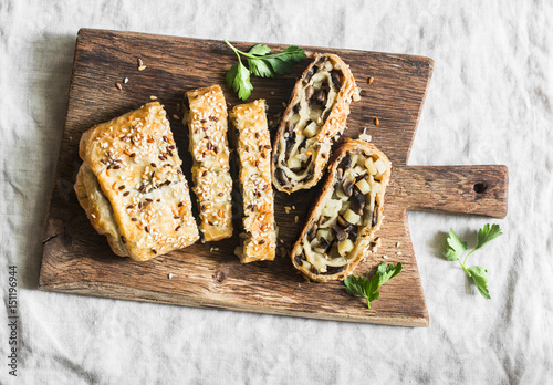 Cuadro en lienzo Mushroom and potato strudel on a rustic wooden cutting board, top view