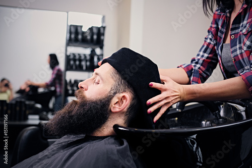 Hairdresser washing bearded men's hair.
