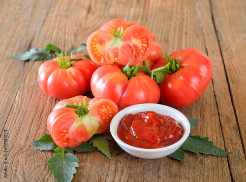 Fresh tomato and ketchup on wooden background