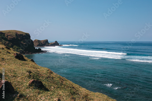 Rocky coast of the ocean with green hills and azure water, Indonesia, Lombok