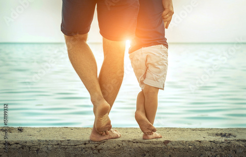 Father and son stay on the sea beach under sunlight at summer ti
