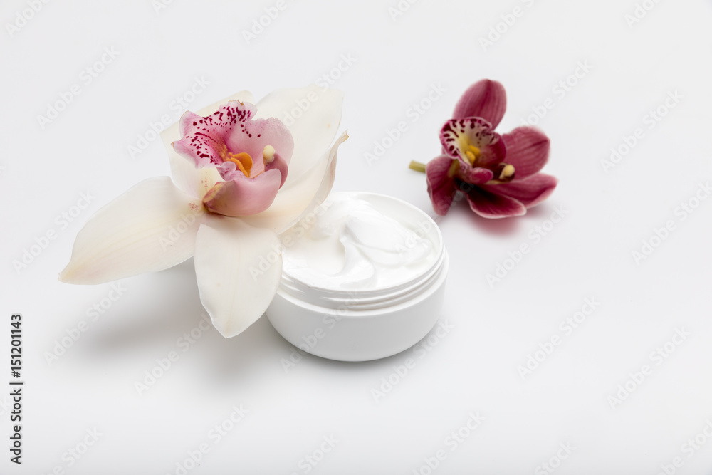 Close-up view of organic cream in container with orchids isolated on white