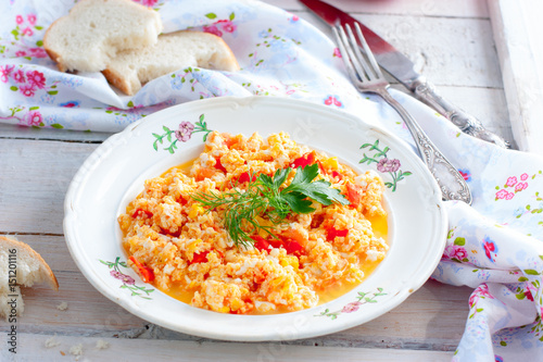 Scrambled eggs with tomatoes and cheese on a plate with white bread, horizontal