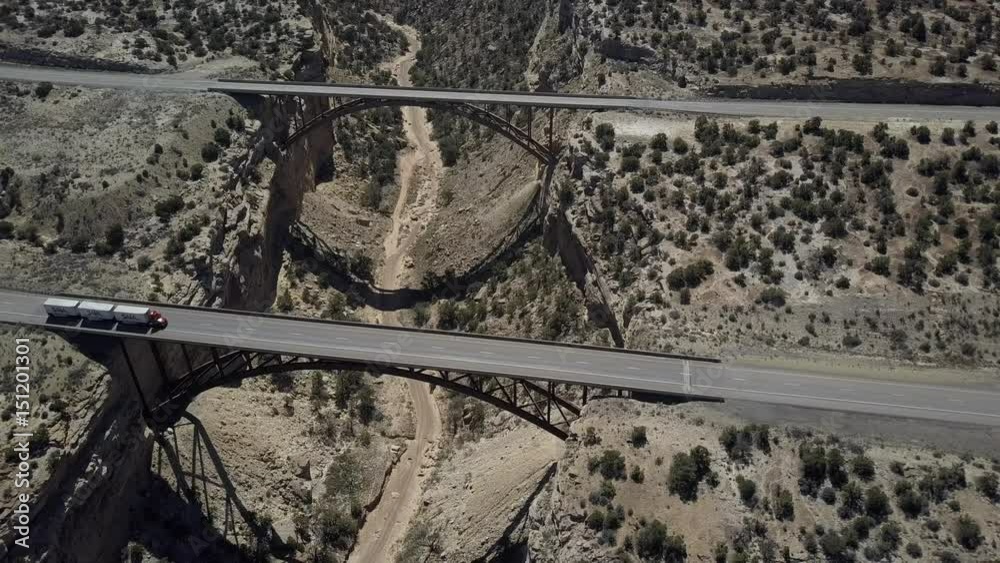 Aerial double span Eagle Canyon Bridge Utah desert overhead. Double span interstate I-70 highway crosses deep gorge. Travel traffic overhead drone. San Rafael geologic desert landscape.